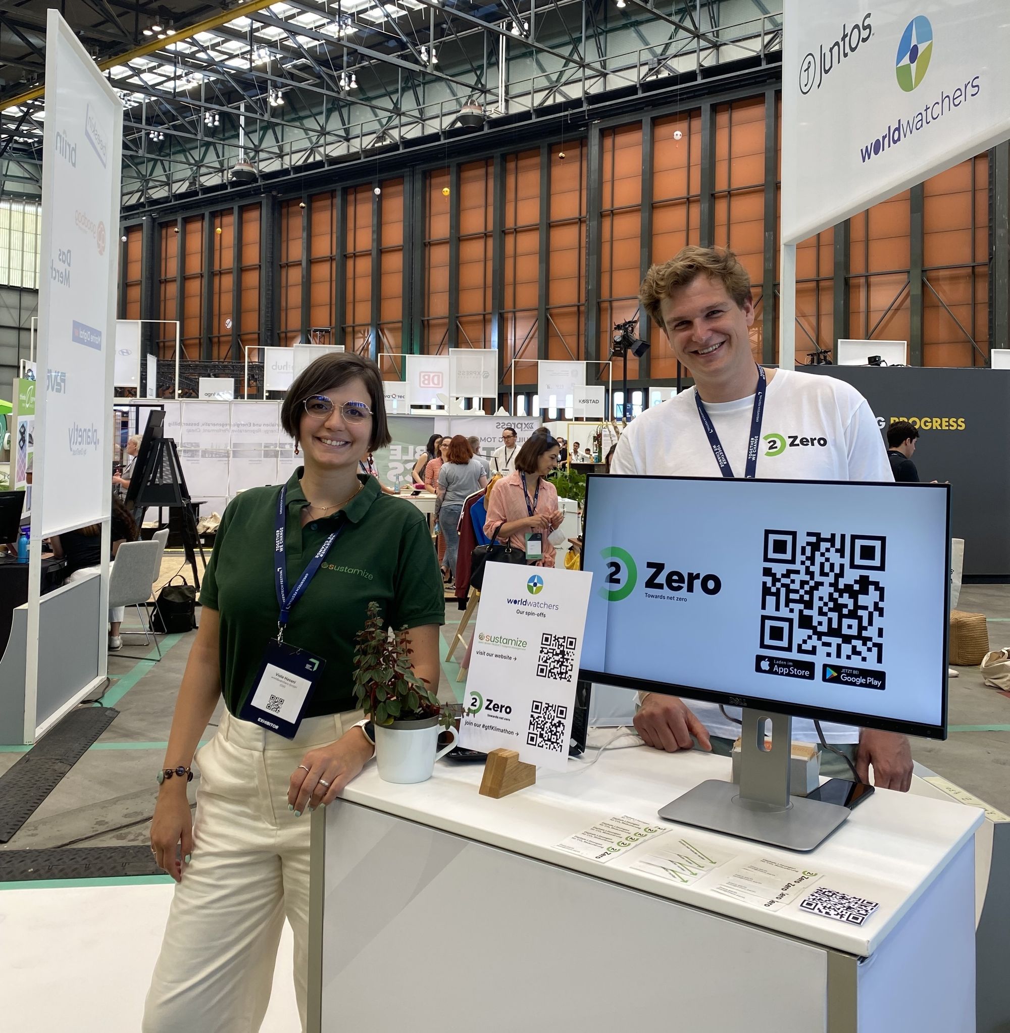 Max steht neben Sustamize und präsentiert 2zero auf einem Bildschirm.