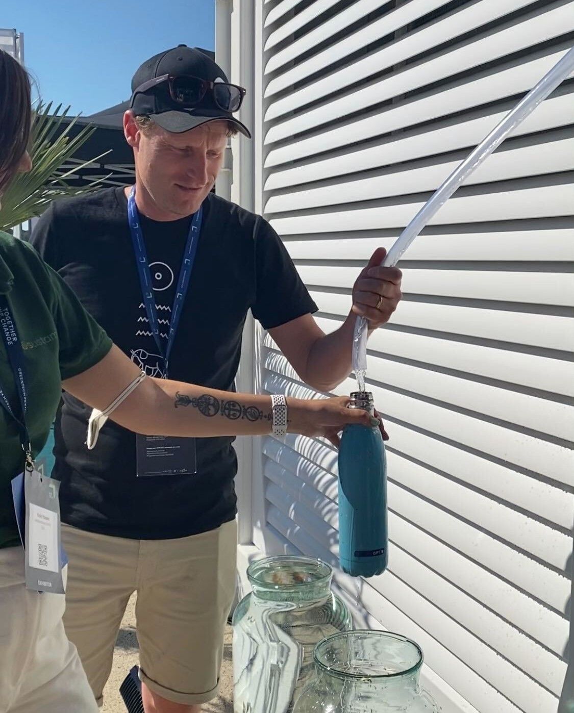 Wir zapfen Wasser aus einem durchsichtigen Schlauch in eine Flasche ab.